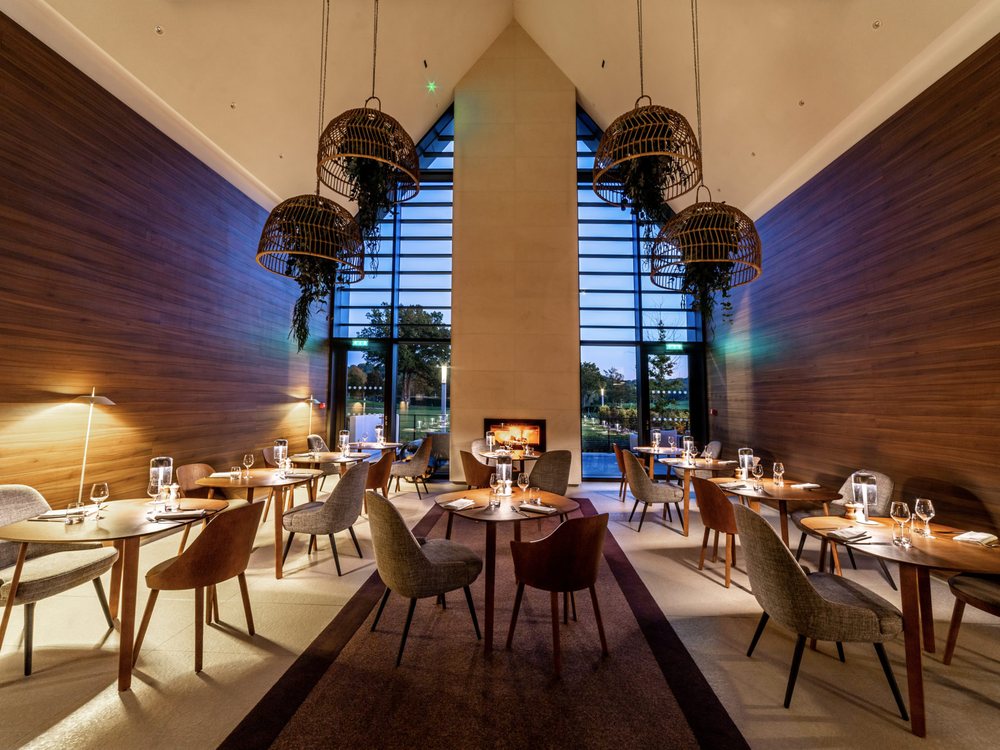 Le restaurant du Domaine des Vanneaux, sa cheminée et sa grande baie vitrée ouverte sur le parc