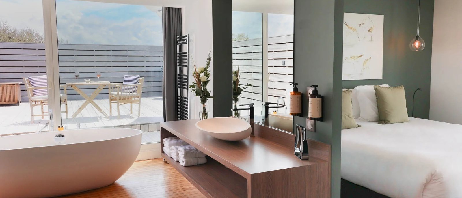 La Suite Panoramique du Grand Large, sa baignoire îlot, sa vasque en bois, son lit et sa terrasse derrière la baie vitrée