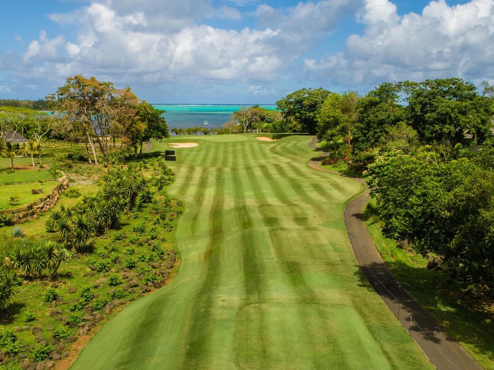 Un fairway rayé d'Anahita Golf qui descend entre les arbres vers le lagon turquoise