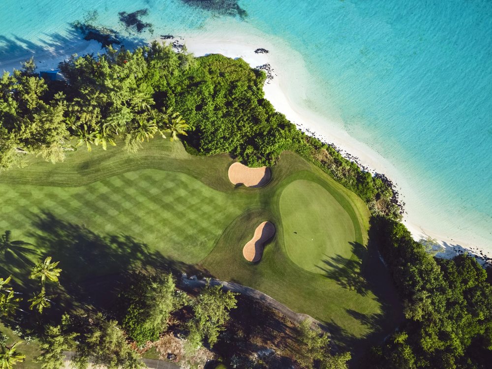 Un green et ses bunkers vus du ciel, au bord de la plage et du lagon turquoise de l'île aux Cerfs