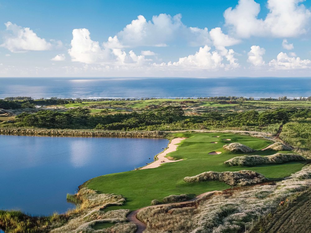 Un fairway de La Réserve Golf Links entre les herbes hautes, au bord d'un plan d'eau, l'océan à l'horizon
