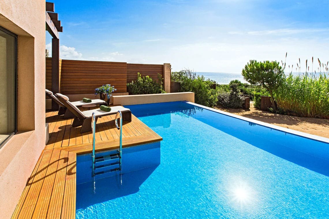Piscine privée à débordement d'une chambre du Romanos, terrasse en bois et mer Ionienne au fond