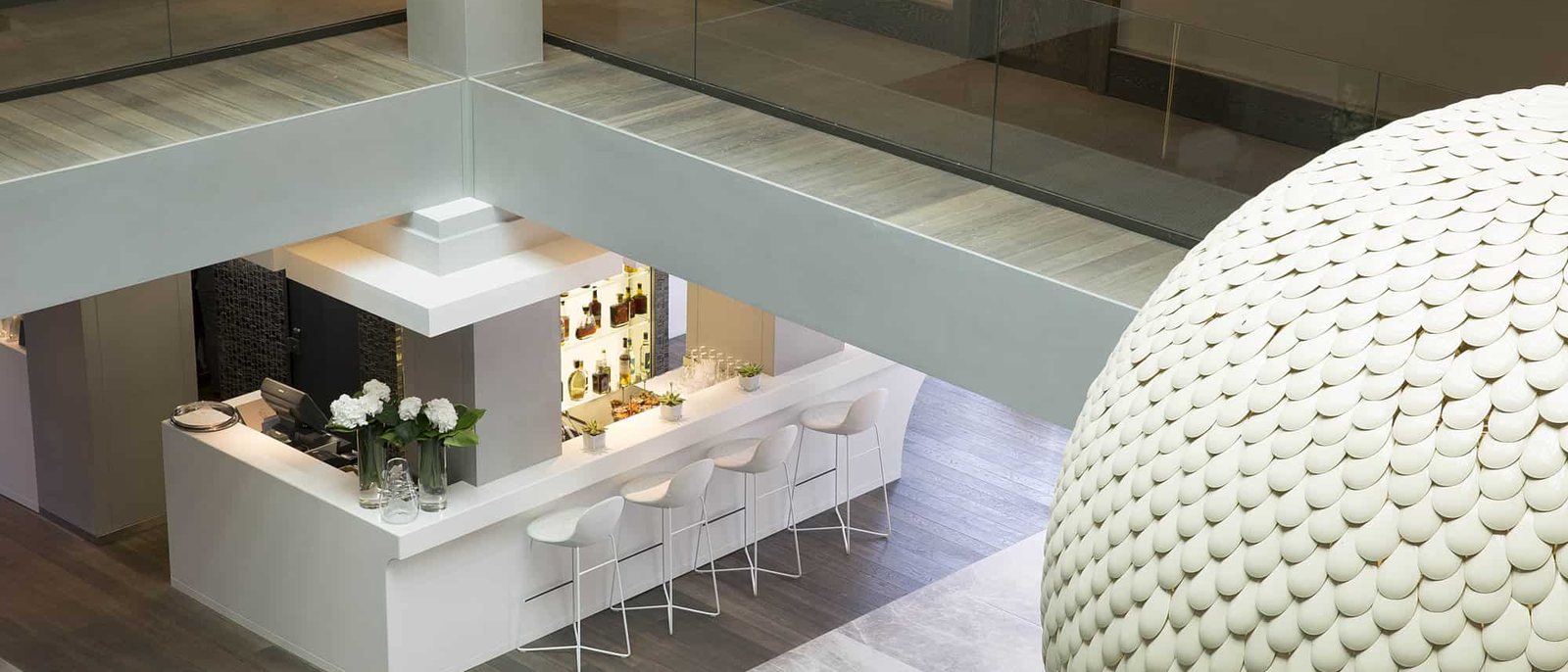 Le hall de l'Hôtel de Paris Saint-Tropez vu depuis les étages, le bar de l'Atrium et le grand lustre de pétales d'aluminium