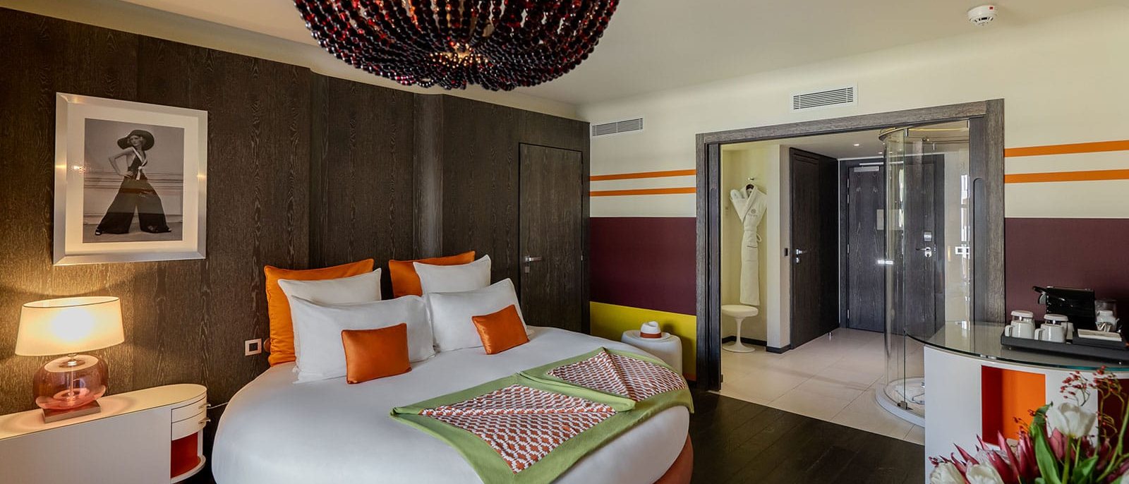 Une chambre de l'Hôtel de Paris Saint-Tropez, son lit rond aux coussins orange et son lustre de perles rouges