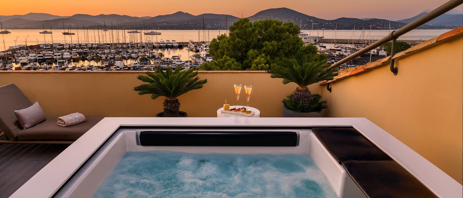 Le jacuzzi de la terrasse de la suite Dolce Vita au coucher du soleil, le port et le golfe de Saint-Tropez en contrebas