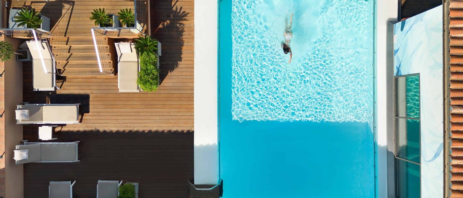 La piscine du toit de l'Hôtel de Paris vue d'en haut, eau turquoise, terrasse en bois et transats