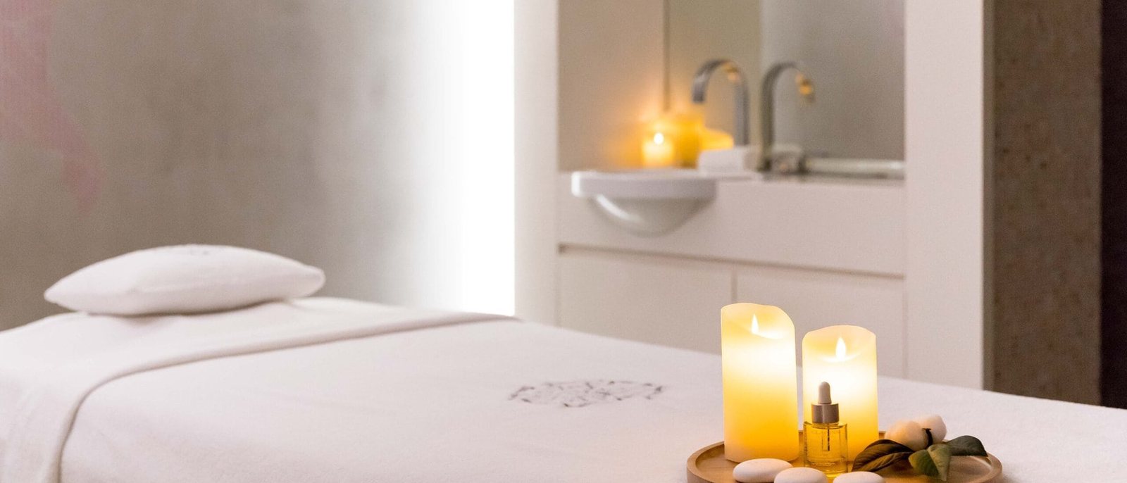 Une salle de soin du Spa by Clarins, table de massage blanche et bougies allumées