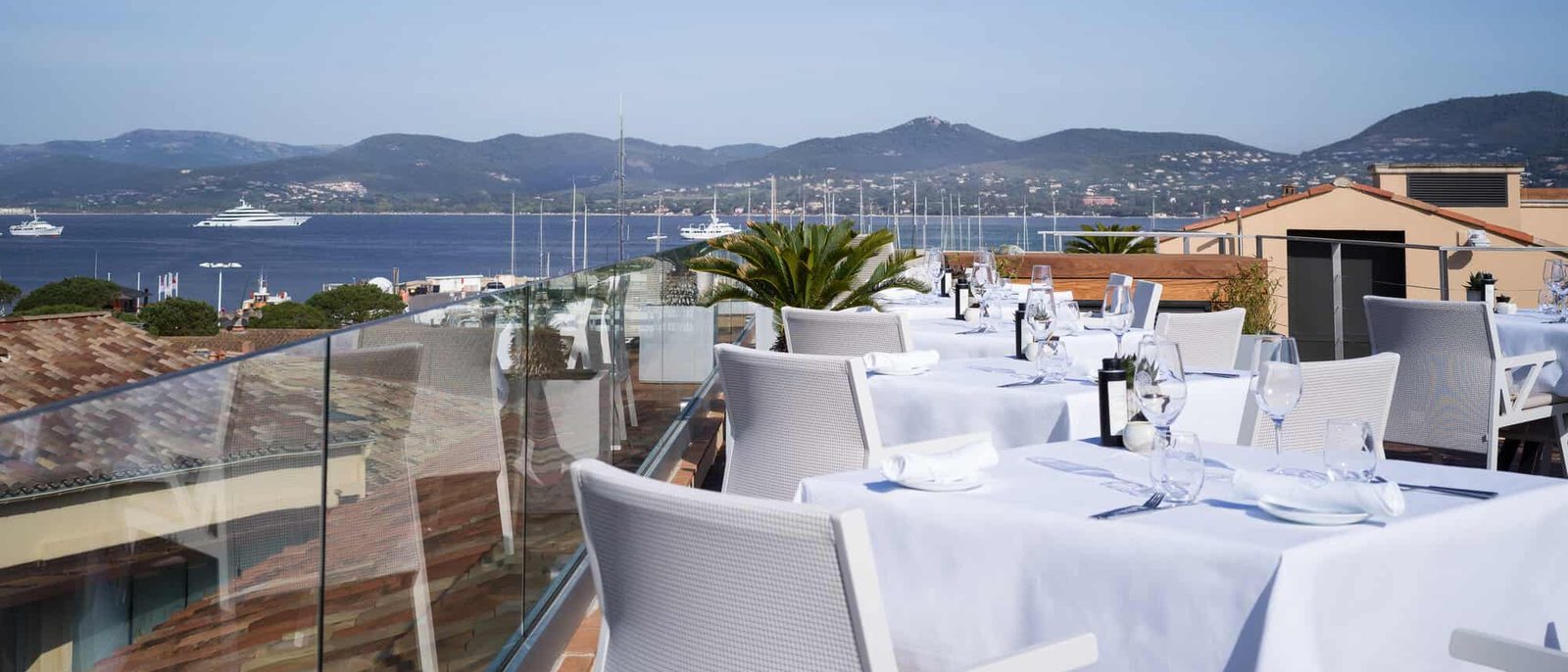 Les tables dressées du restaurant Les Toits, face au golfe de Saint-Tropez et aux collines du Var