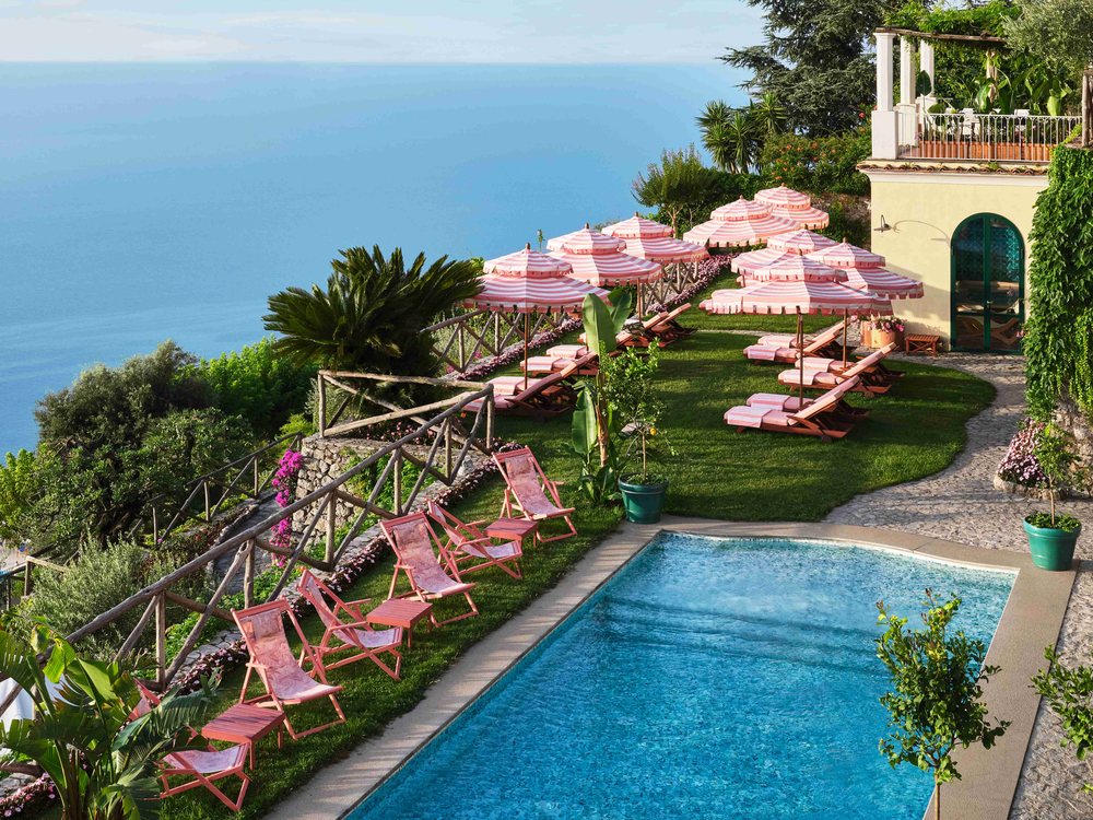 La piscine extérieure chauffée du Palazzo Avino, ses transats roses et le golfe de Salerne en contrebas