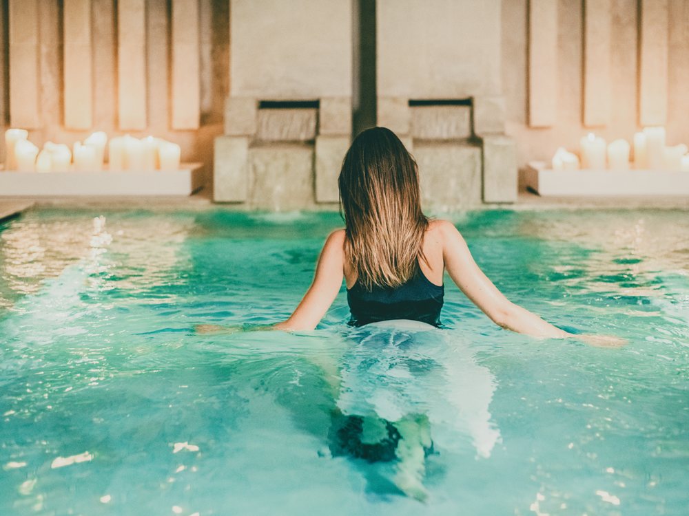 Une baigneuse dans la piscine intérieure du Vair Spa de Borgo Egnazia, sous des fontaines de pierre