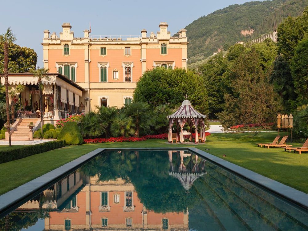 La piscine de la Villa Feltrinelli dans son jardin, la façade de la villa et un kiosque reflétés dans l'eau