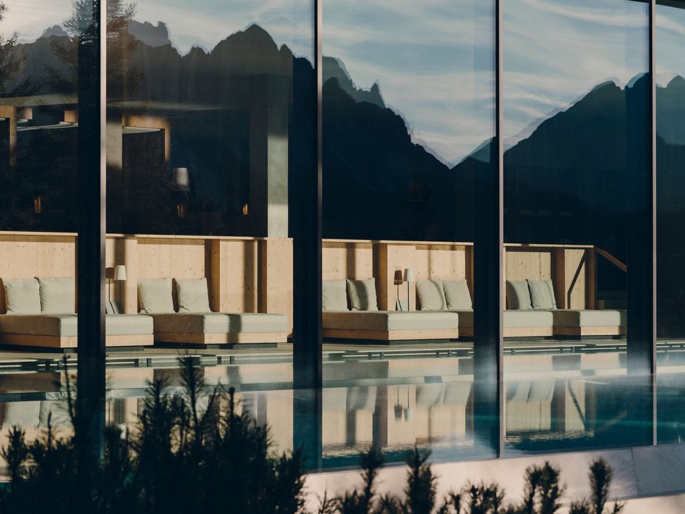 Le bassin intérieur du spa de Forestis, ses banquettes et ses baies vitrées où se reflètent les Dolomites