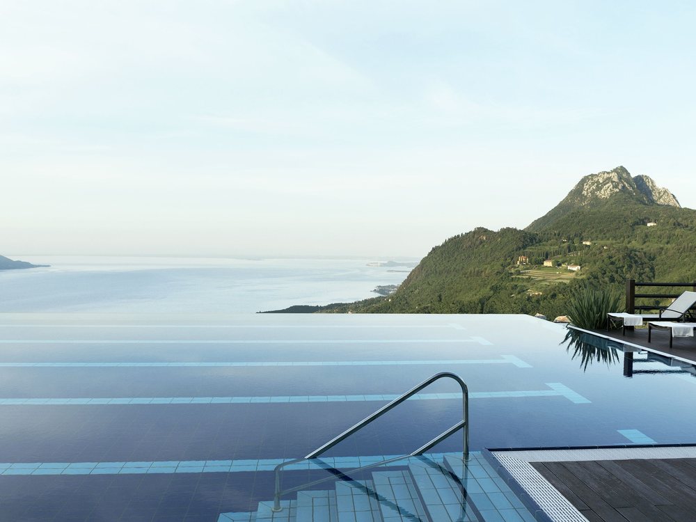 La piscine à débordement du Lefay Lago di Garda, ses marches et le lac de Garde dans la brume, au pied d'un promontoire