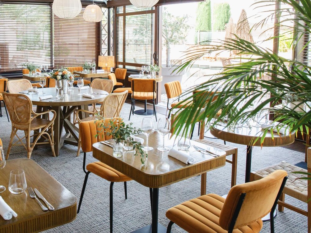 La salle de L'Aquarama, ses chaises de rotin et ses tables de bois clair ouvertes sur la verdure