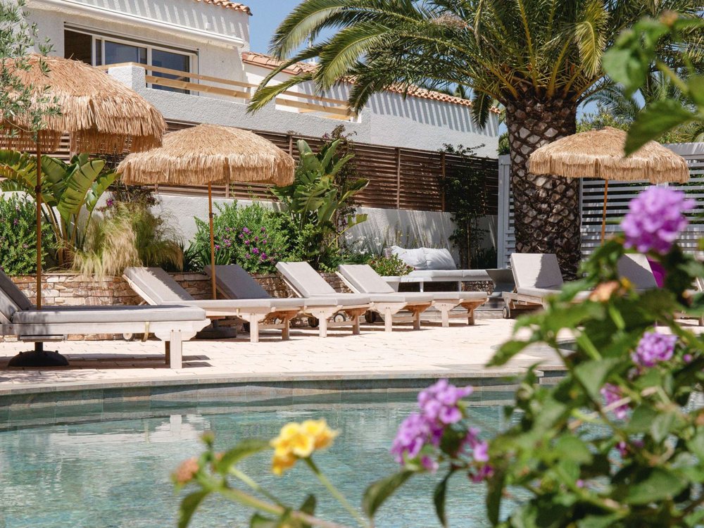 La piscine extérieure de l'Île de la Lagune, ses paillotes et ses transats parmi les palmiers et les fleurs