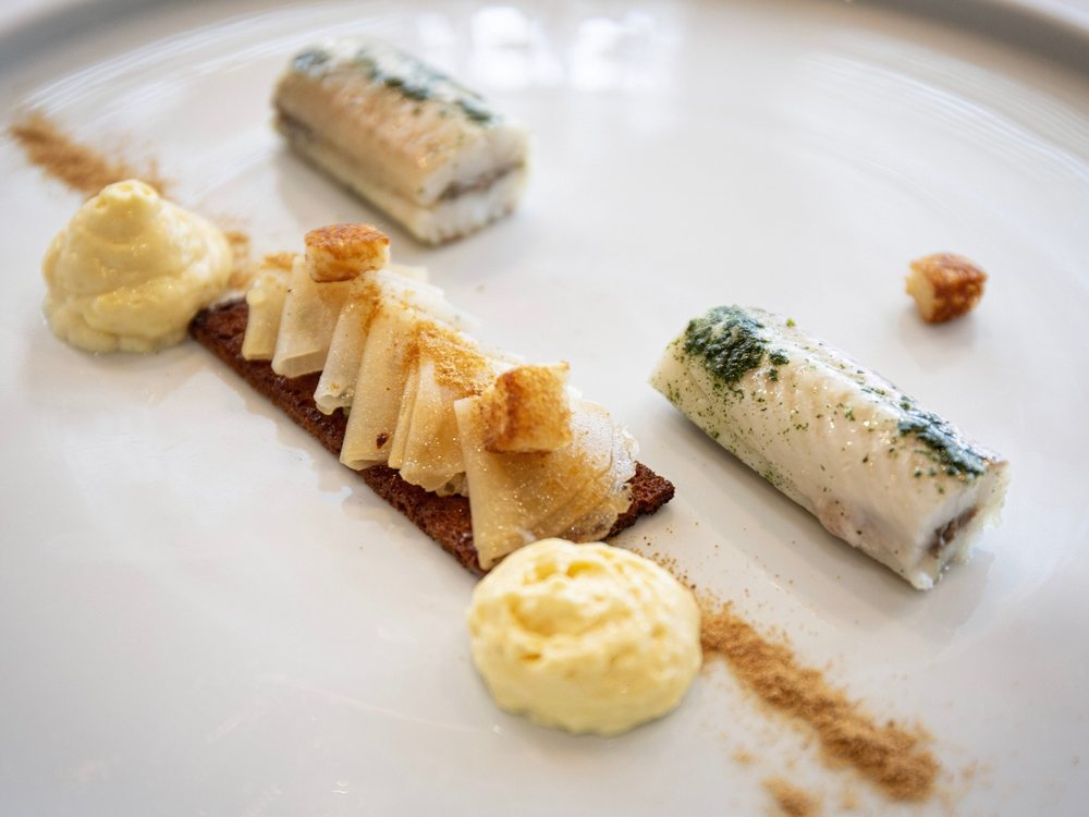 Une assiette de L'Almandin, poisson roulé et crèmes, dressée sur une assiette blanche