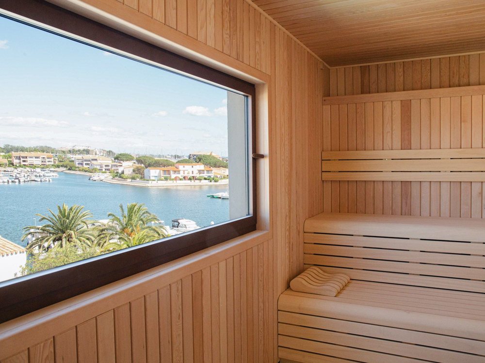 Le sauna du spa de l'Île de la Lagune, ses bancs de bois clair et sa grande baie ouverte sur la lagune