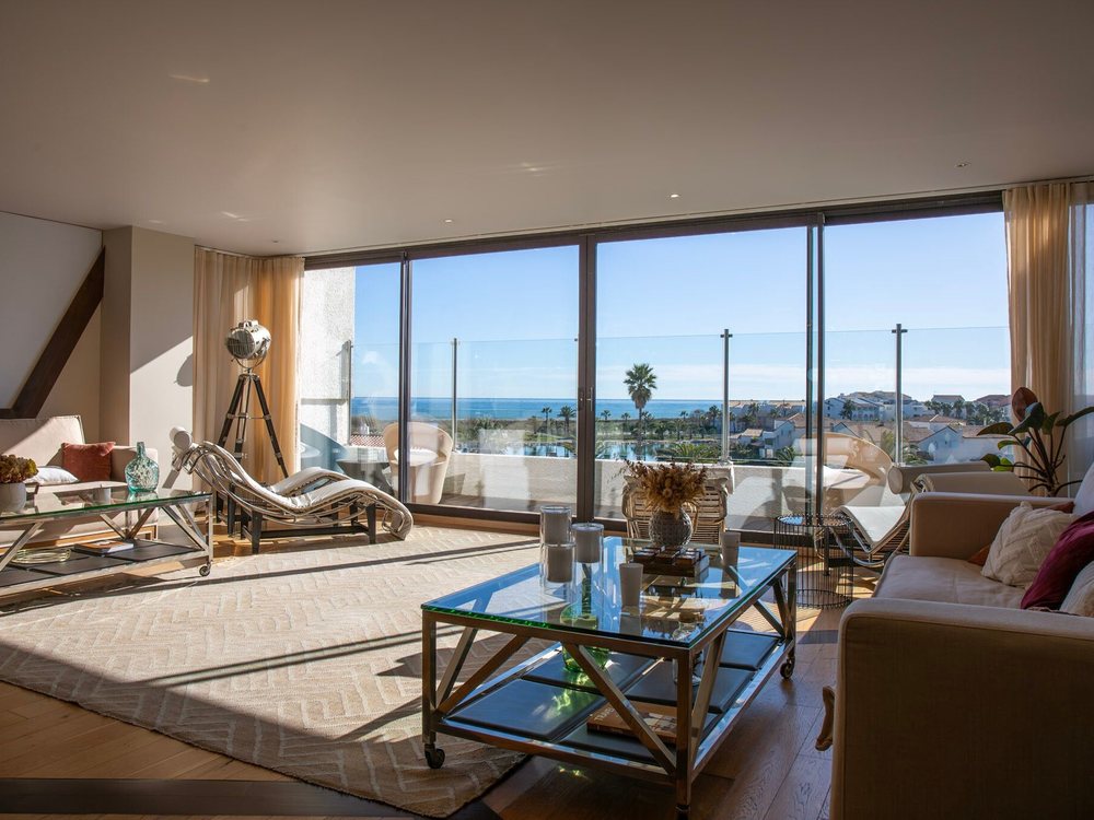 Le salon d'une suite de l'Île de la Lagune, ses baies vitrées ouvertes sur une terrasse et sur la mer
