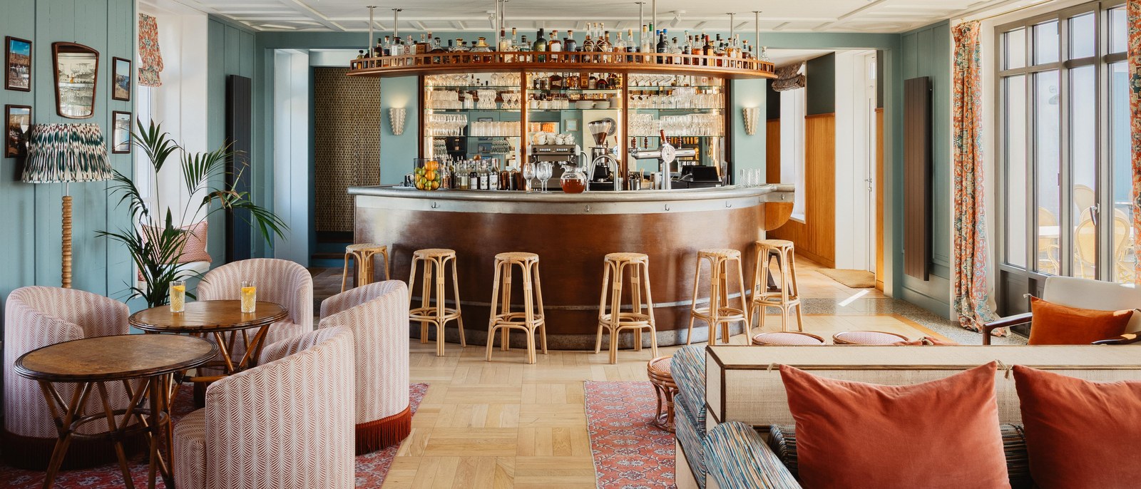Le Bar 1802 de La Mission, comptoir de bois, tabourets, fauteuils rayés et canapés aux coussins rouges