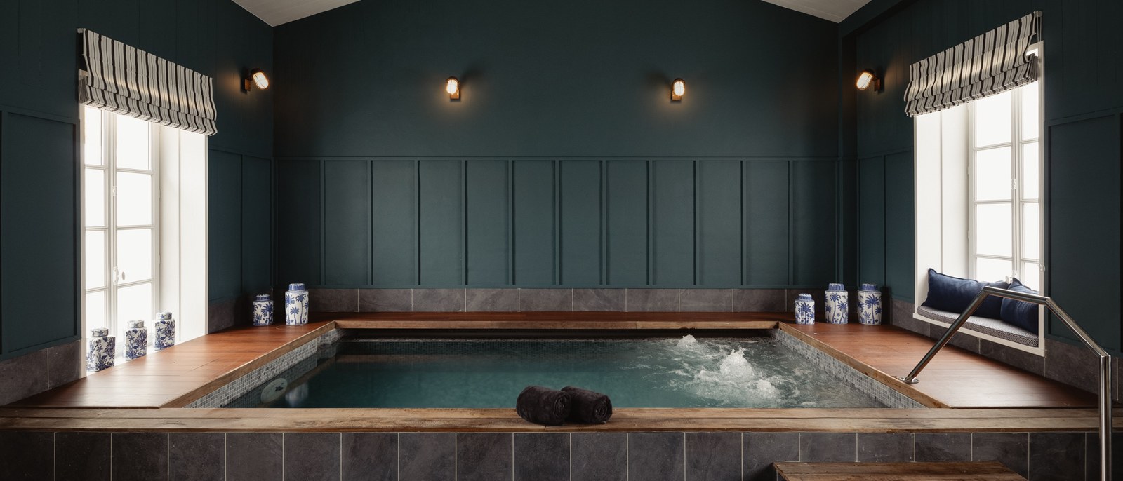 Le bassin du spa Nuxe de La Mission, dans une salle aux boiseries vert sombre, fenêtre à store rayé