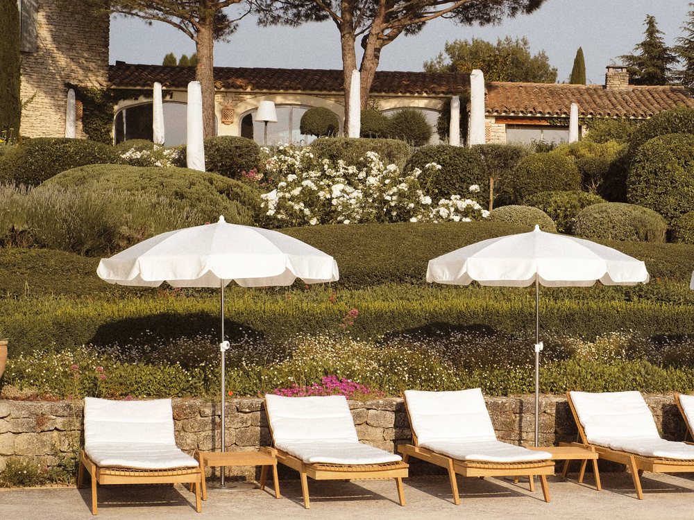 Les transats et parasols blancs de la piscine de Capelongue, entre les haies taillées, au-dessus de Bonnieux