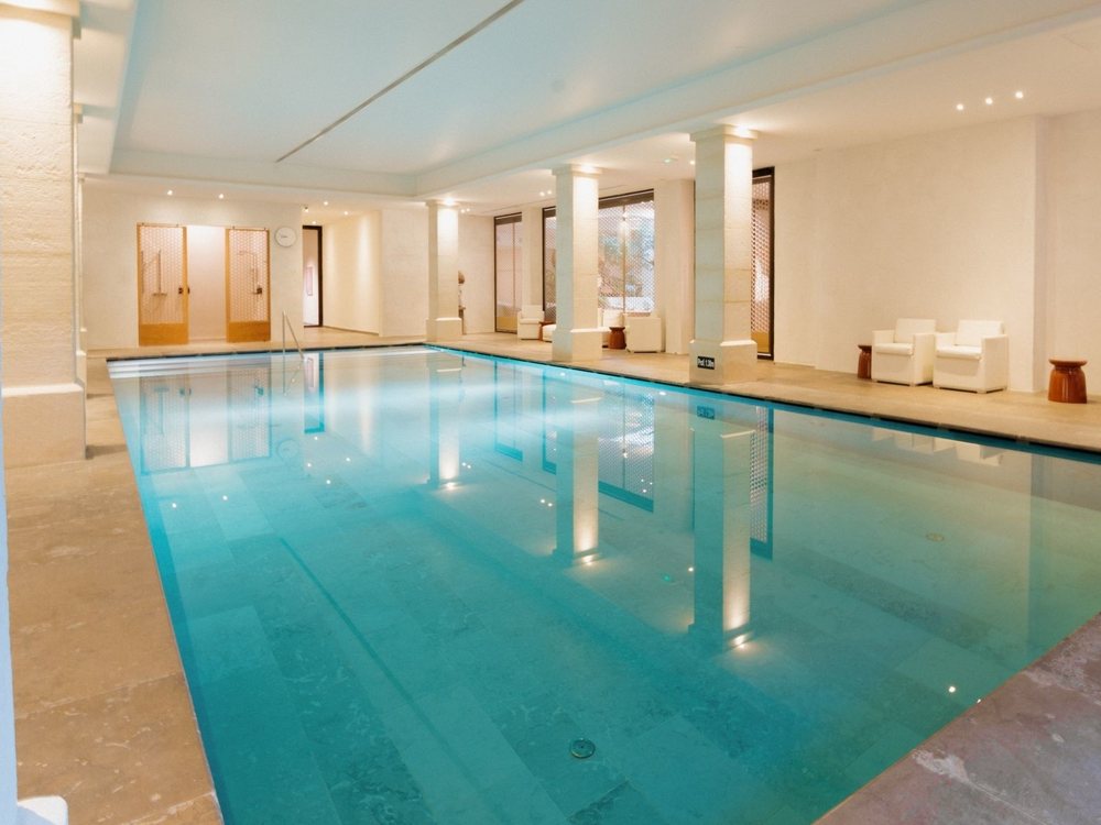 La piscine intérieure chauffée du spa de Coquillade, sa colonnade et ses lits de repos blancs