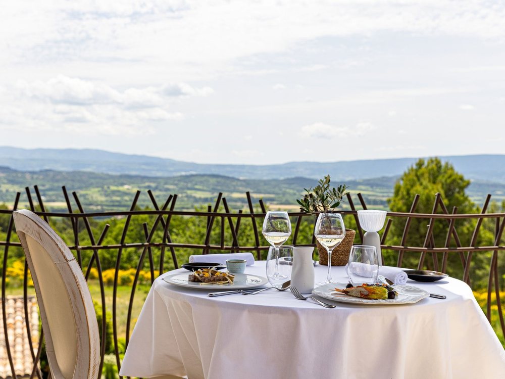 Une table dressée sur la terrasse du Mas des Herbes Blanches, face au panorama du Luberon