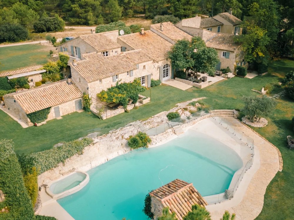 Vue aérienne du Mas de la Rose, ses bergeries de pierre et sa piscine au milieu des jardins et des pins