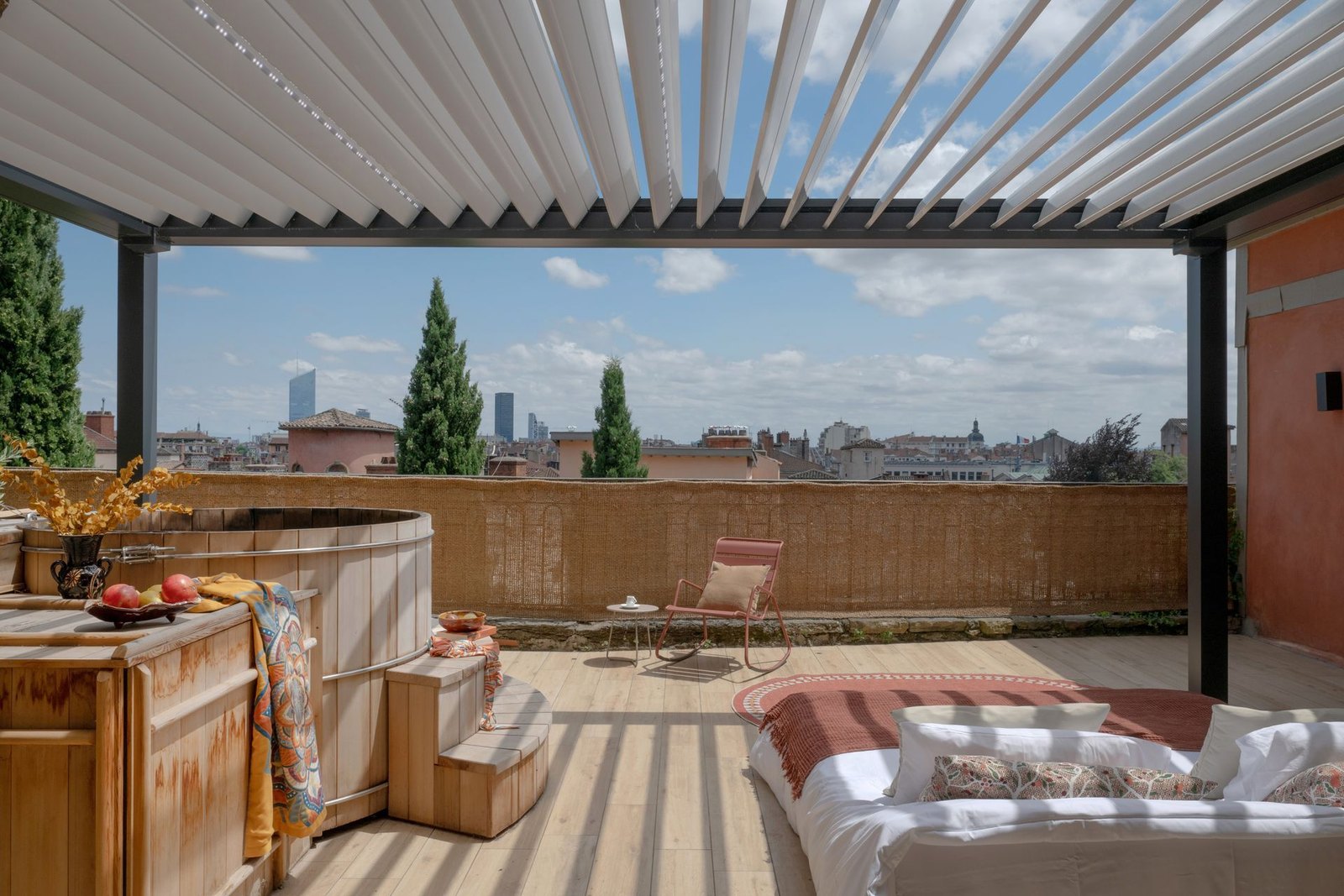Bain nordique en bois et lit sous pergola sur la terrasse d'une suite de La Tour Rose, vue sur les toits de Lyon