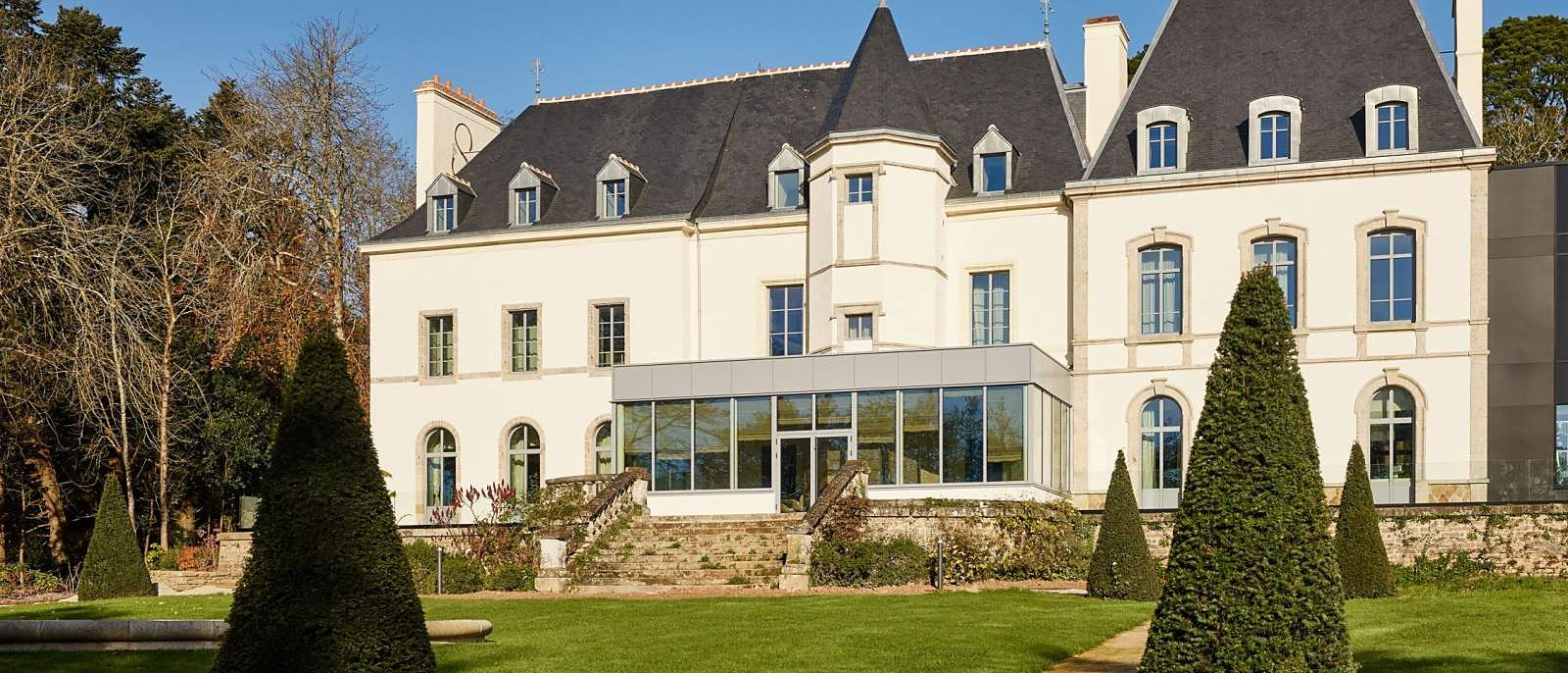 La façade du château du Domaine du Liziec et ses jardins taillés