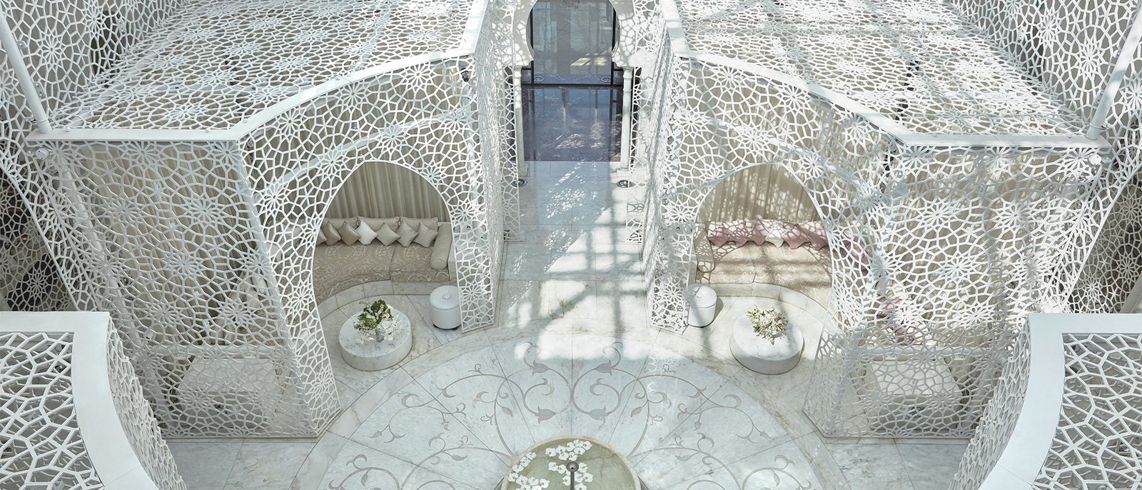 L'atrium blanc et ajouré du spa du Royal Mansour Marrakech, ses alcôves et ses banquettes autour d'un bassin