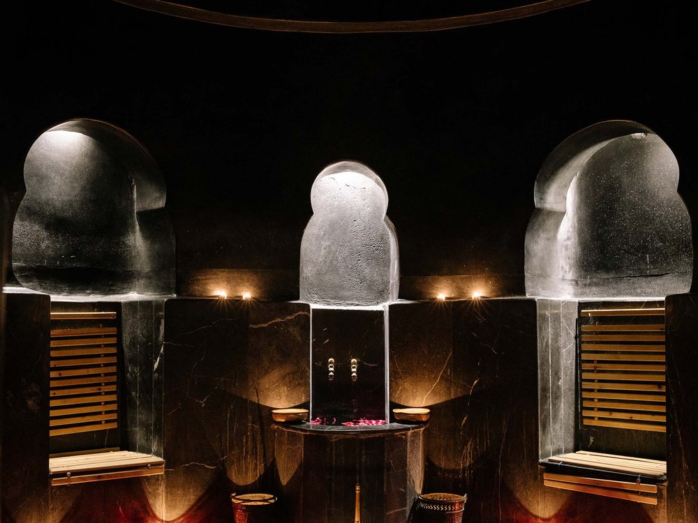 Le hammam de l'Heure Bleue Palais, ses murs de tadelakt noir, ses niches cintrées et ses bougies