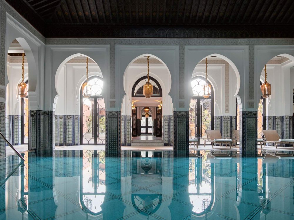 La piscine intérieure du spa de La Mamounia, ses arcades blanches et ses lanternes, en enfilade
