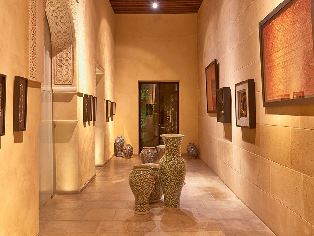 Un couloir du spa du Riad Fès, ses murs ocre, ses tableaux et ses grandes jarres de céramique