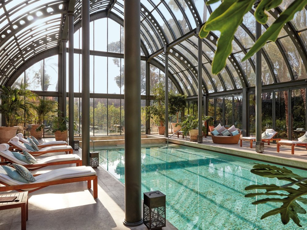La piscine couverte du Royal Mansour sous sa grande verrière, ses transats et ses palmiers