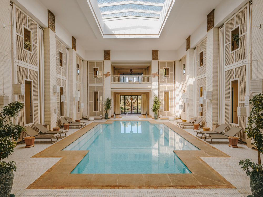 La grande piscine intérieure du spa du Fairmont Royal Palm, sous une verrière, entre des colonnes claires