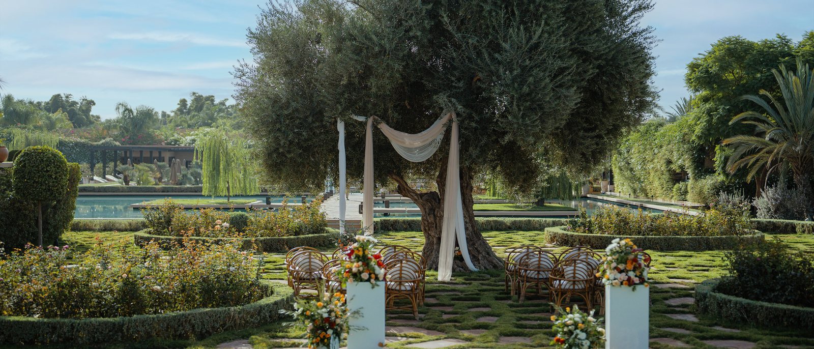 Une arche de cérémonie drapée de voilages sous un olivier, dans le jardin andalou du Mandarin Oriental, Marrakech