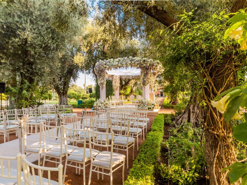 Une cérémonie dressée sous les oliviers des jardins de La Mamounia, chaises blanches et kiosque fleuri