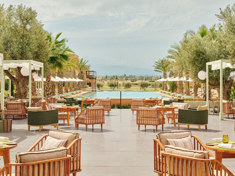 La terrasse du Pavillon du Park Hyatt Marrakech, fauteuils en rotin sous les pergolas, piscine et Atlas au loin
