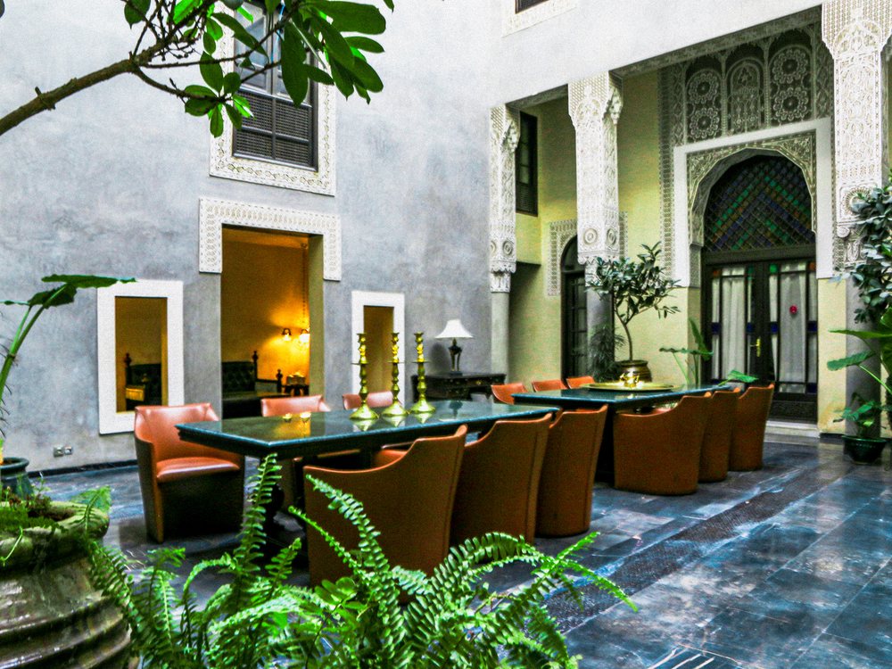 Le Patio Baroque du Riad Fès, longue table dressée pour un dîner privé entre fougères et façades sculptées