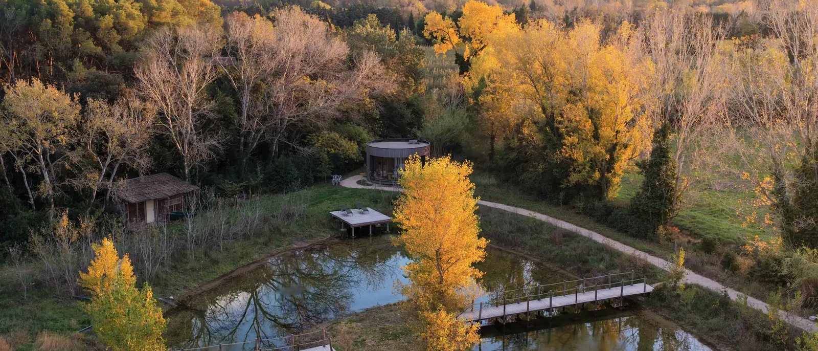 L'étang du domaine vu du ciel à l'automne, ses pontons et les suites immersives entre les arbres