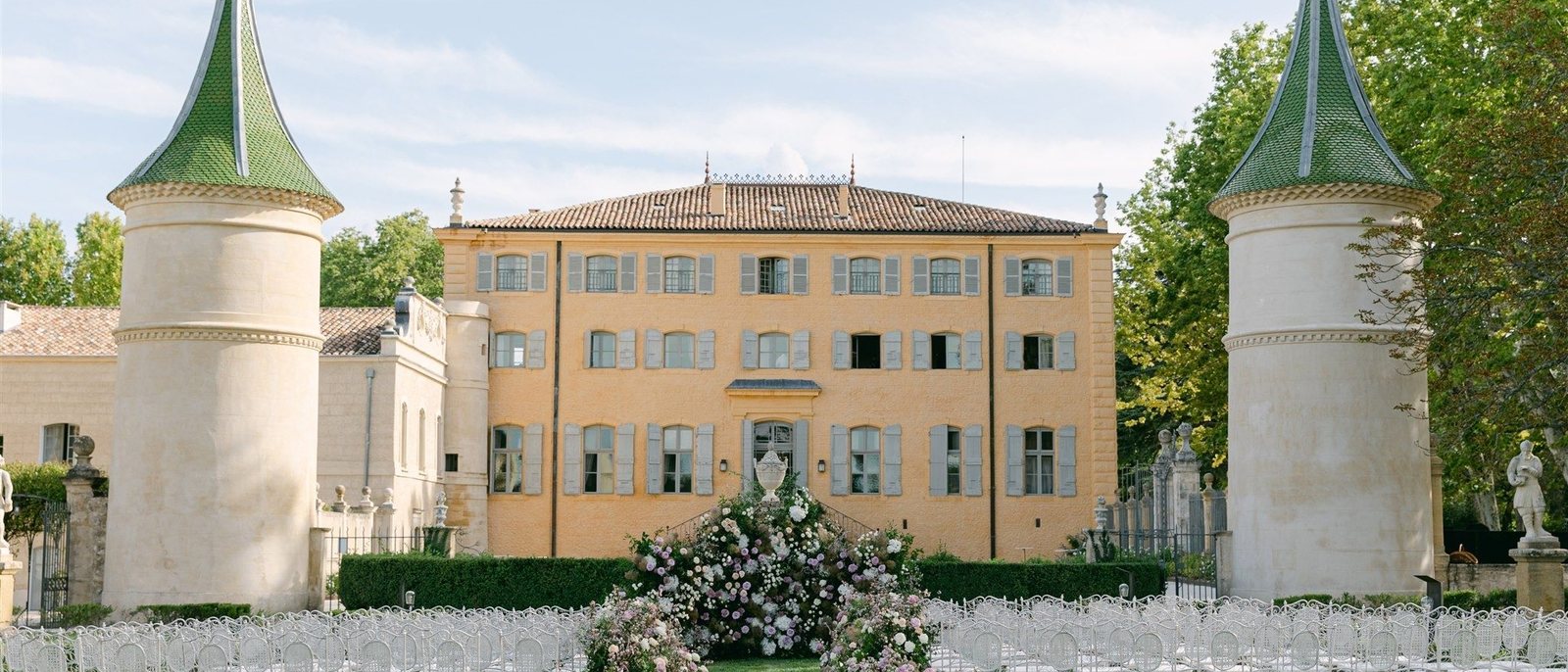 Une cérémonie de mariage dressée sur la pelouse du Château de Fonscolombe, entre ses deux tours aux toits verts
