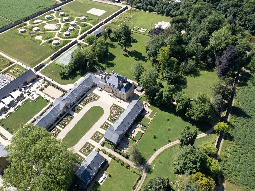Vue aérienne du Domaine Le Mezo, le château, ses communs et ses jardins au milieu du parc boisé