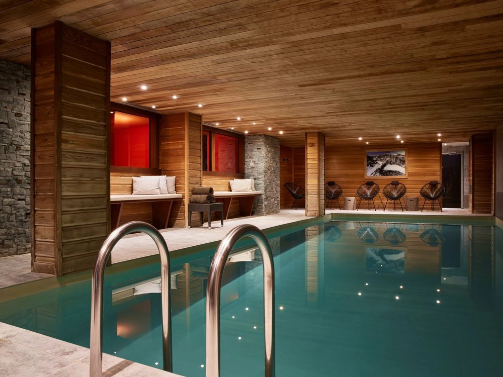 La piscine intérieure chauffée de L'Arboisie, sous un plafond de bois, avec ses fauteuils de repos