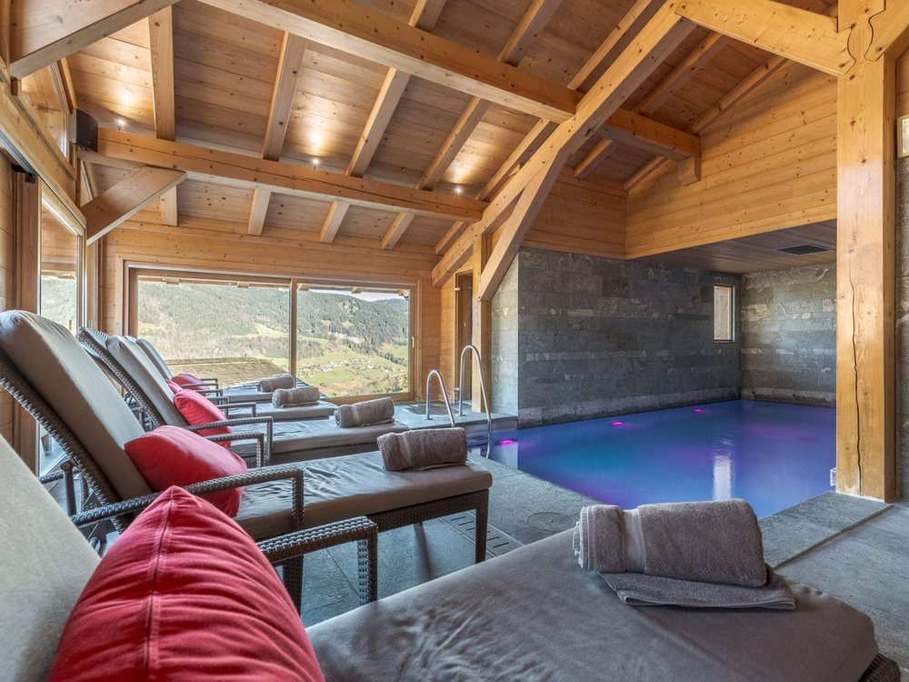 La piscine intérieure chauffée du Flocons de Sel sous sa charpente de bois, face aux sapins