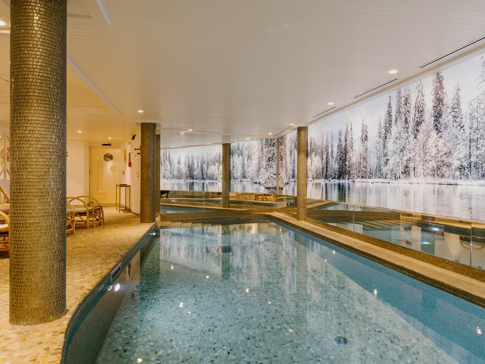 La piscine intérieure chauffée du Grand Hôtel du Soleil d'Or, bordée d'une fresque de forêt enneigée