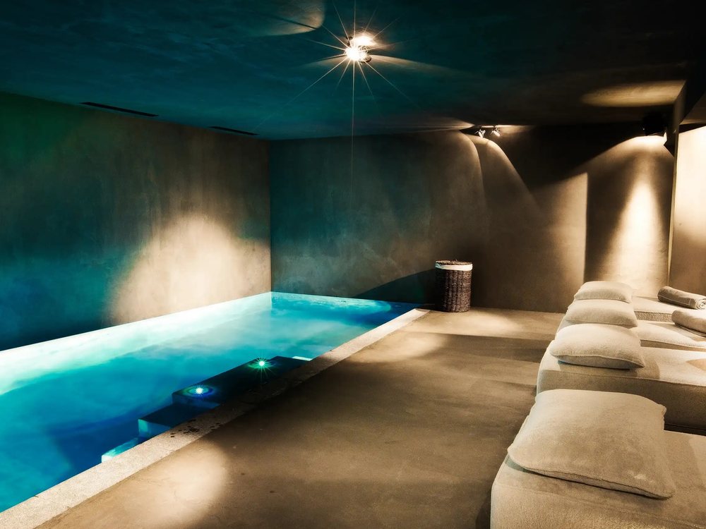 La piscine intérieure chauffée du Chalet Zannier, éclairée de bleu, et ses banquettes de repos