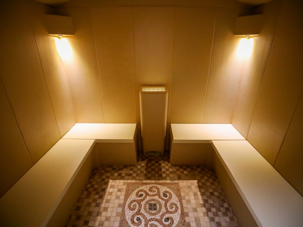 Le hammam de La Mandia, ses banquettes claires et sa mosaïque au sol, sous deux appliques