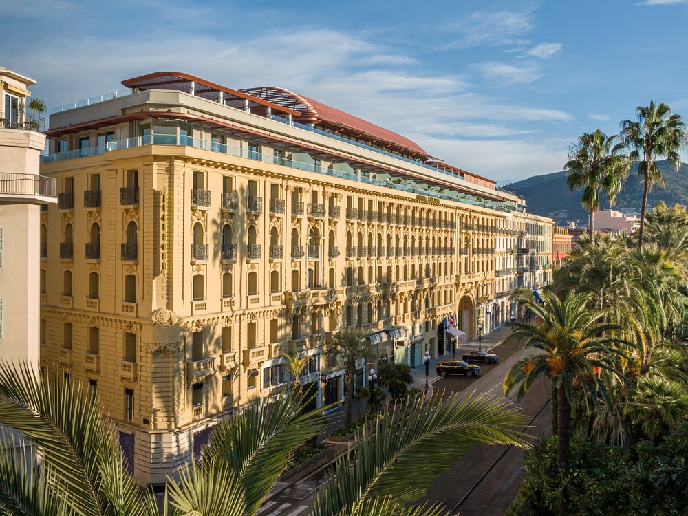 La façade Belle Époque de l'Anantara Plaza Nice, entre les palmiers du jardin Albert-Ier