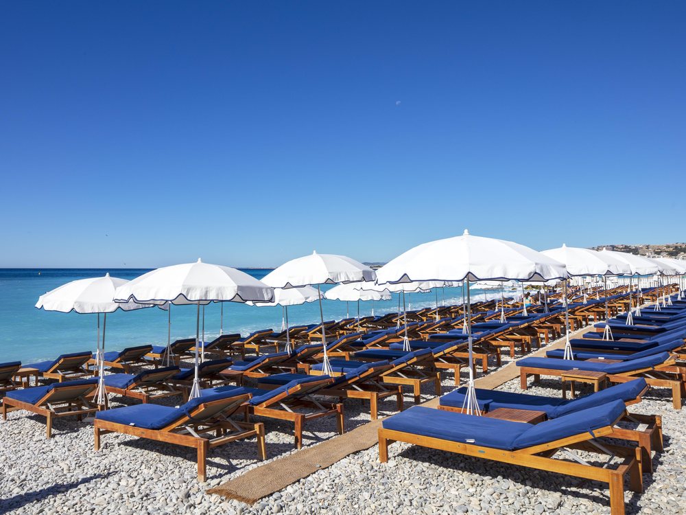 La plage privée du Beau Rivage à Nice, ses transats bleus et ses parasols blancs sur les galets